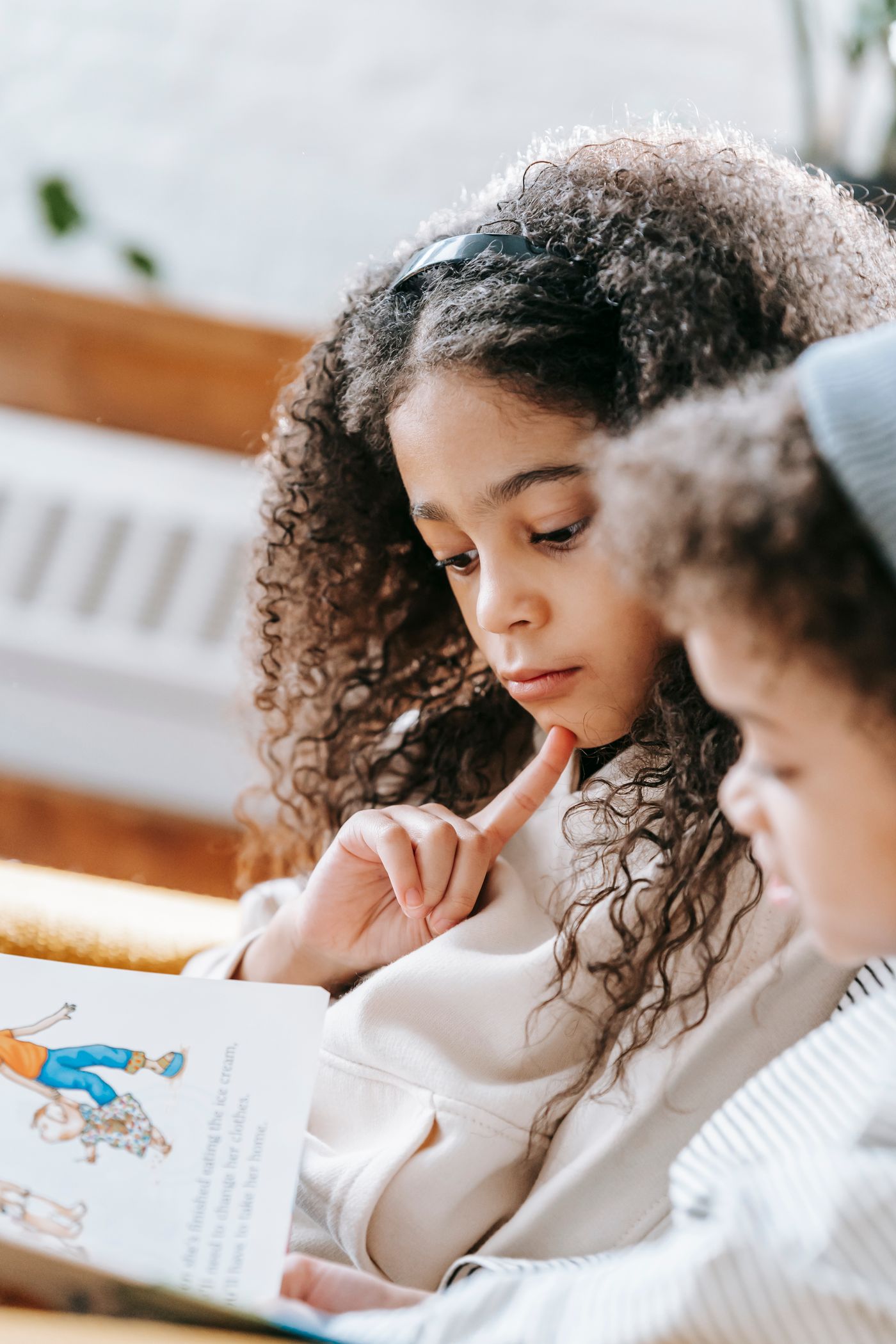 Two Black children enjoying a book together