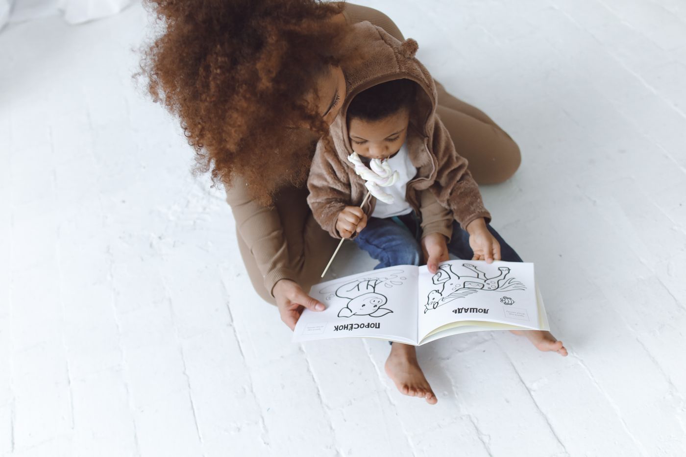 A Black parent and young child looking at a picture book together